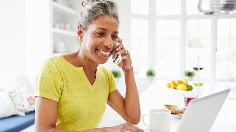 lady smiling on phone working on a laptop